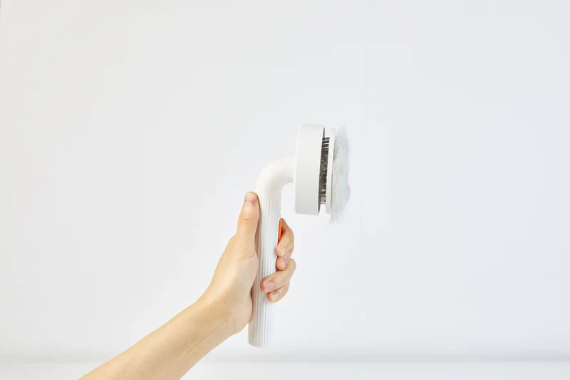 Четката Brush 2 в ръка, с кълбо събрана козина върху иглите